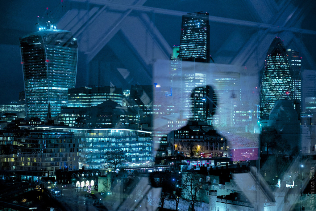 A man is reflected against London's financial district skyline.